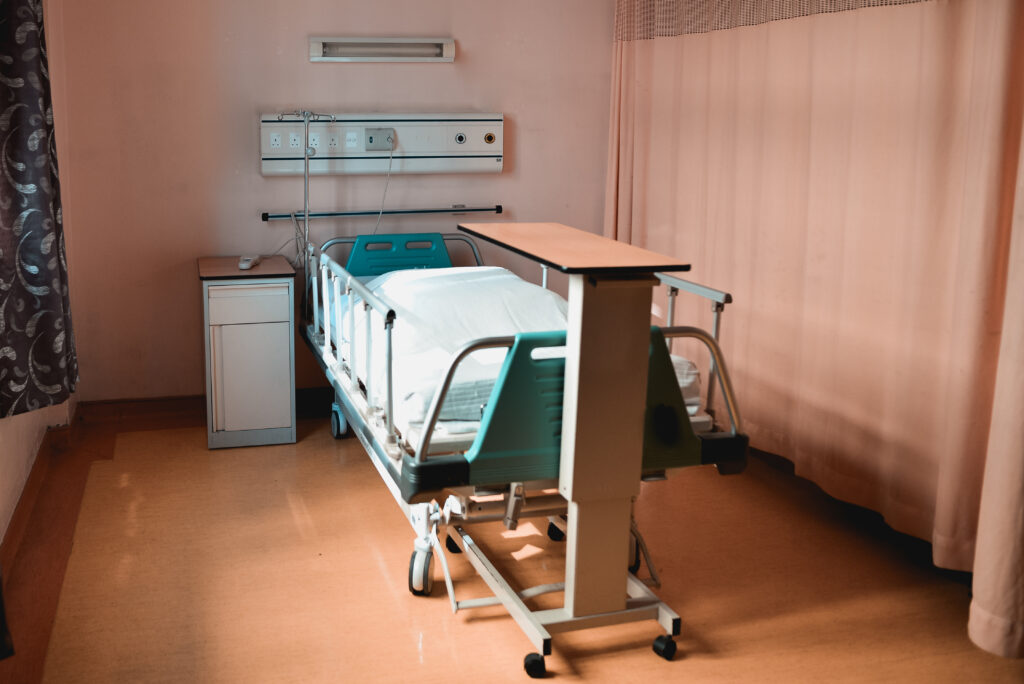 Shot of a modern hospital bed and a wooden desk near a curtain inside a clinic